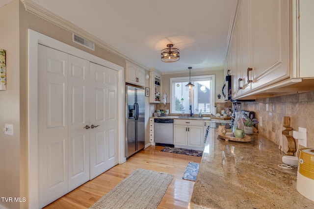 kitchen featuring light hardwood / wood-style floors, stainless steel appliances, decorative light fixtures, and white cabinets