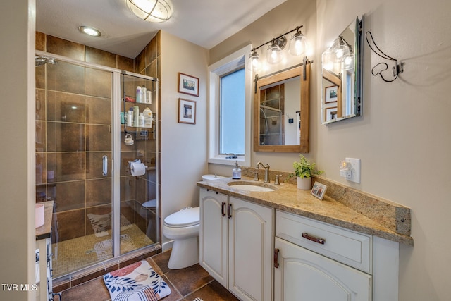 bathroom featuring vanity, a shower with shower door, toilet, and tile patterned floors