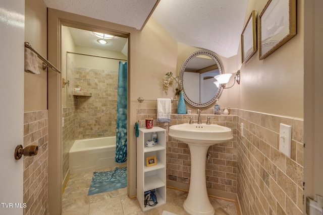 bathroom featuring tile walls, a textured ceiling, and shower / tub combo