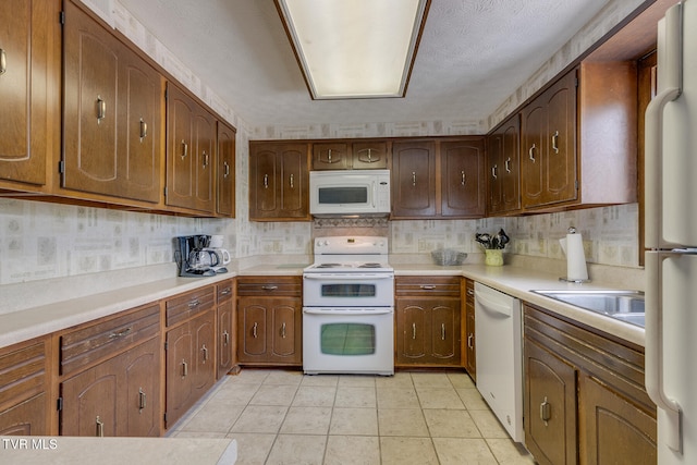 kitchen with a textured ceiling, white appliances, and light tile patterned floors