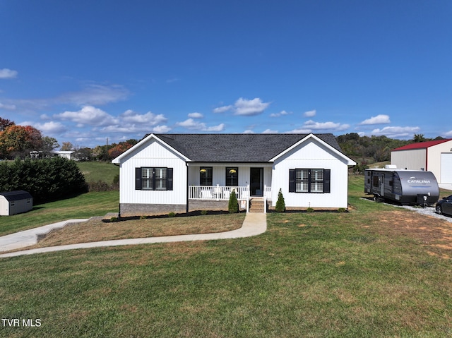 view of front of home featuring an outdoor structure, a front yard, and covered porch