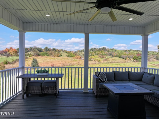 wooden deck featuring ceiling fan, a lawn, and an outdoor living space