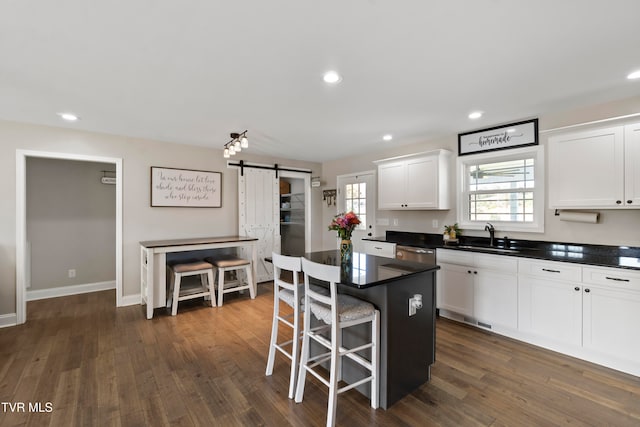 kitchen with a kitchen island, sink, a barn door, white cabinets, and dark hardwood / wood-style flooring