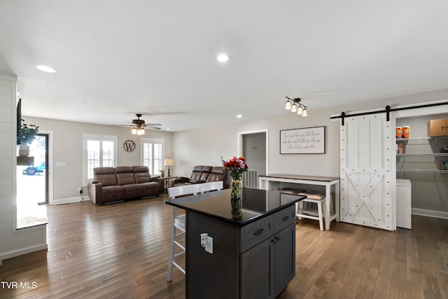 kitchen featuring a breakfast bar area, dark hardwood / wood-style floors, a barn door, and a kitchen island