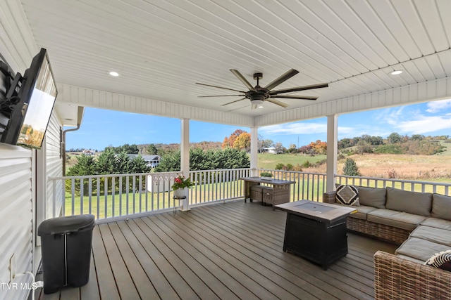 wooden terrace with outdoor lounge area, a lawn, and ceiling fan