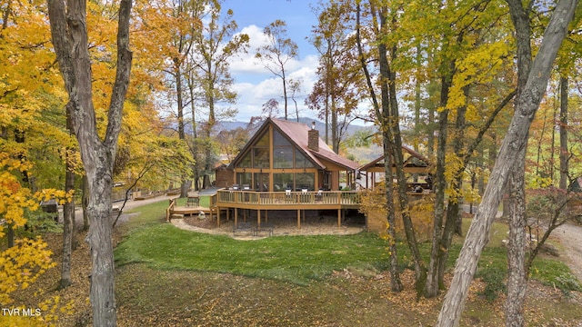 rear view of house with a wooden deck and a lawn