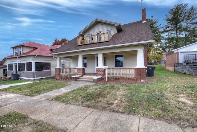 bungalow featuring covered porch, a sunroom, and a front yard