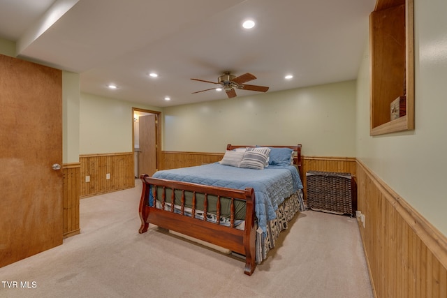 bedroom with wood walls, light colored carpet, and ceiling fan