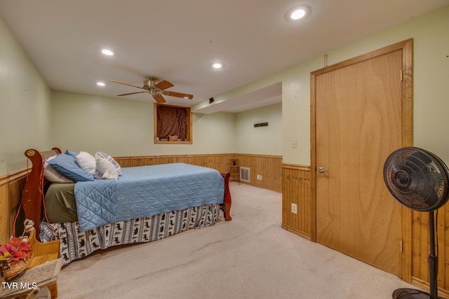 carpeted bedroom featuring ceiling fan and wood walls