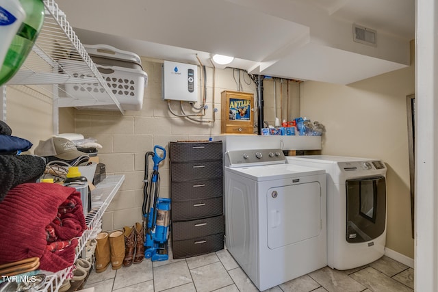 laundry area featuring light tile patterned flooring, independent washer and dryer, and tankless water heater