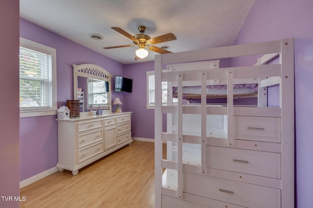 bedroom with light hardwood / wood-style flooring, a textured ceiling, and ceiling fan