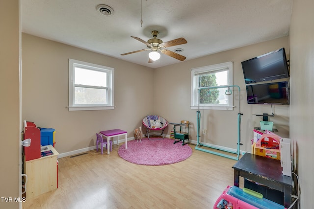 rec room featuring ceiling fan, a textured ceiling, and light wood-type flooring