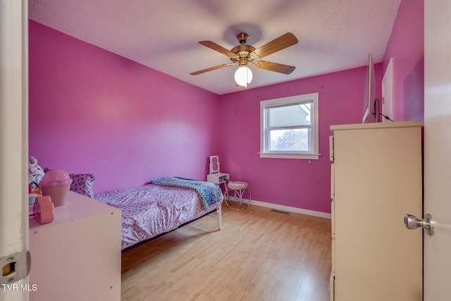 bedroom with a textured ceiling, light wood-type flooring, and ceiling fan