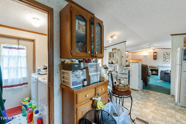 kitchen with ornamental molding, lofted ceiling, a textured ceiling, and ceiling fan