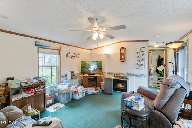 living room with a fireplace, crown molding, a textured ceiling, carpet flooring, and ceiling fan