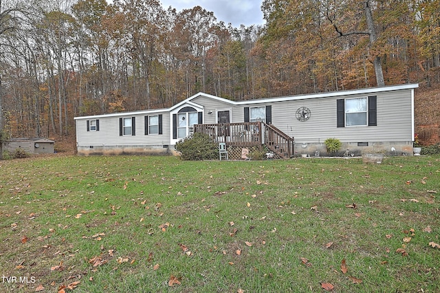 manufactured / mobile home featuring a front lawn, a wooden deck, and a storage shed