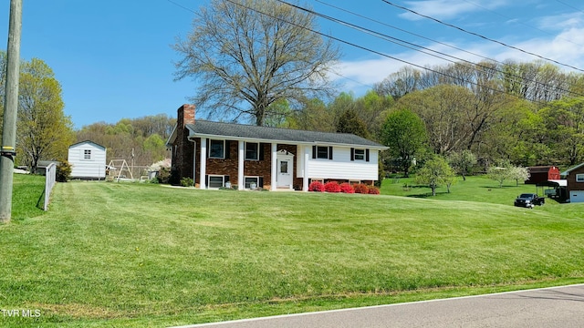 raised ranch featuring a storage unit and a front yard