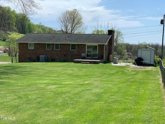 rear view of property with a storage unit, cooling unit, a yard, and a patio area