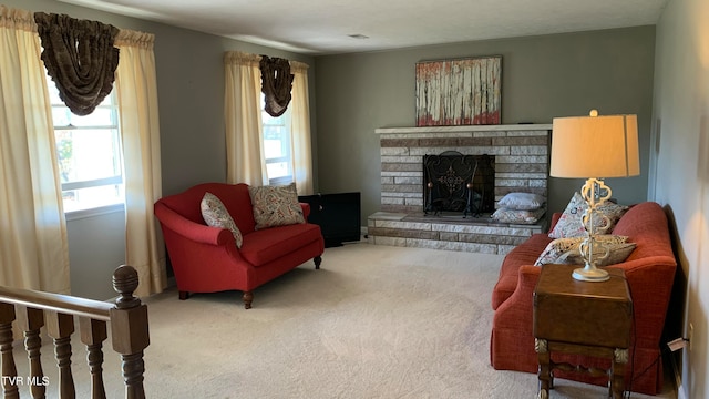 living room featuring a stone fireplace, carpet, and a healthy amount of sunlight