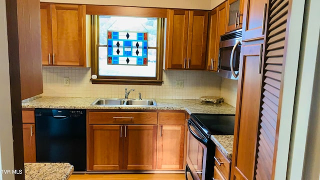 kitchen with decorative backsplash, black appliances, sink, and light stone counters