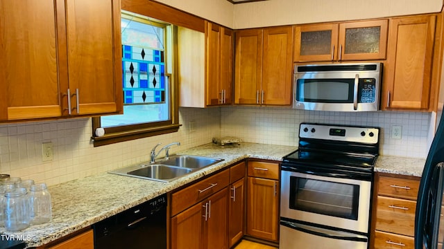 kitchen featuring decorative backsplash, stainless steel appliances, sink, and light stone counters