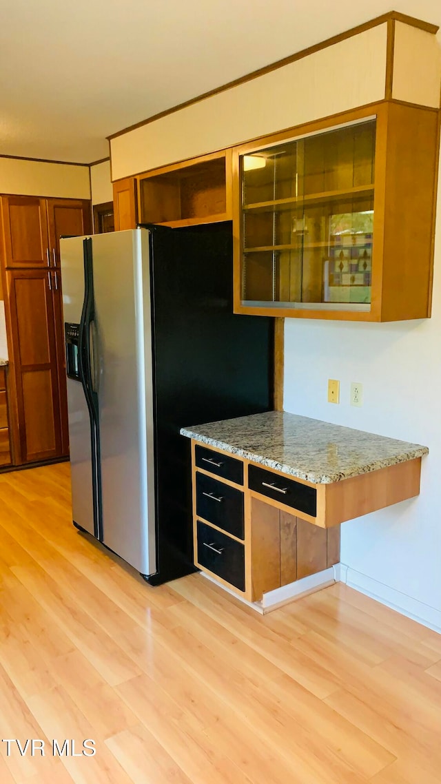 kitchen featuring stainless steel fridge, light stone countertops, and light hardwood / wood-style floors