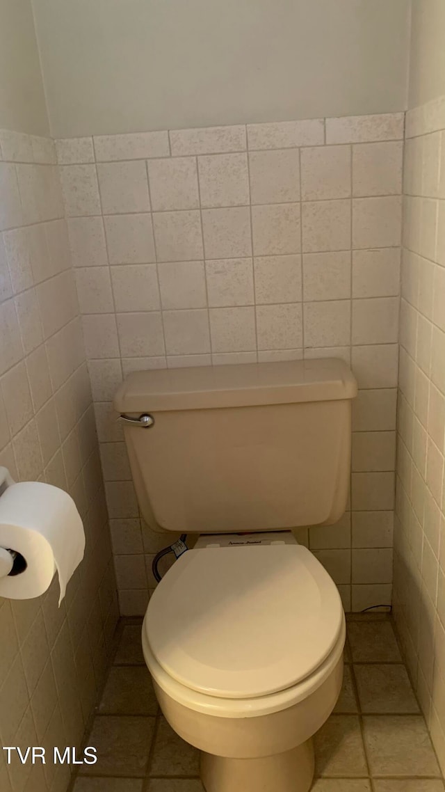 bathroom with toilet, tile walls, and tile patterned flooring