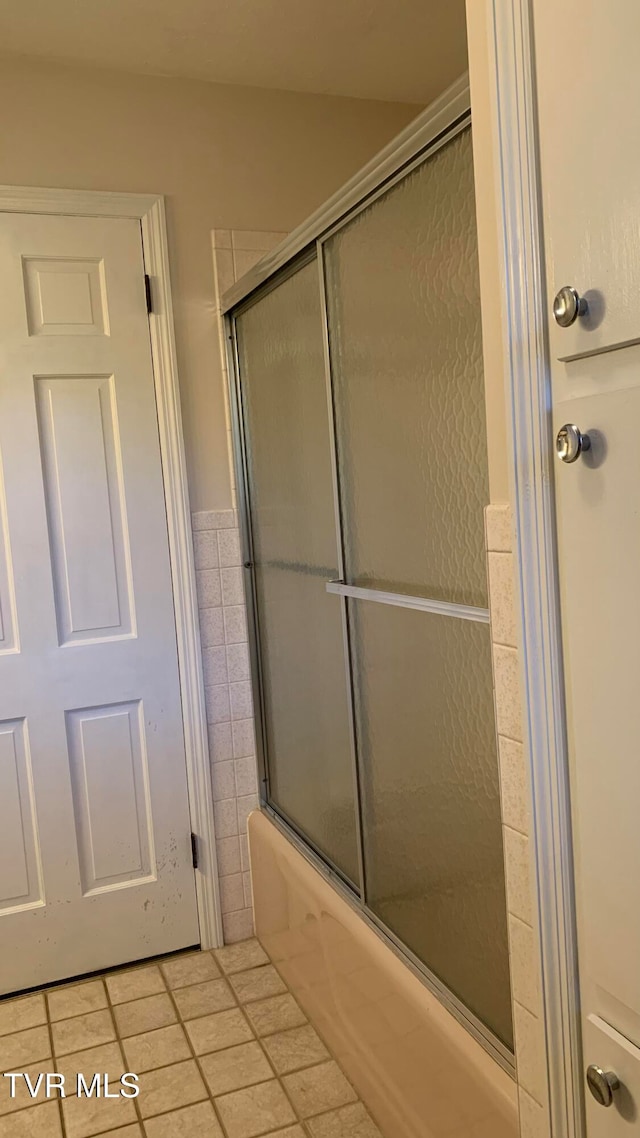 bathroom with combined bath / shower with glass door and tile walls