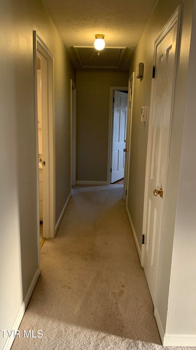 corridor featuring a textured ceiling and light carpet