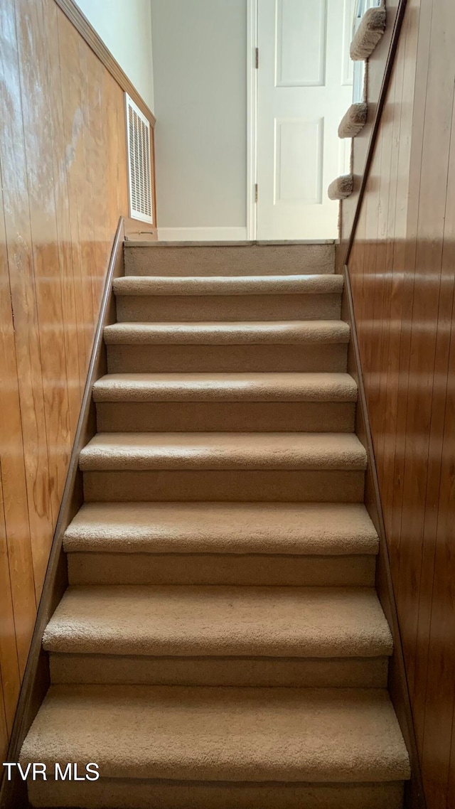 staircase featuring wooden walls