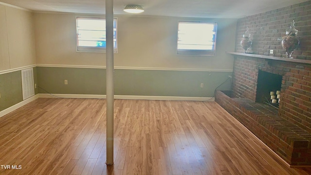 basement with a brick fireplace and hardwood / wood-style floors