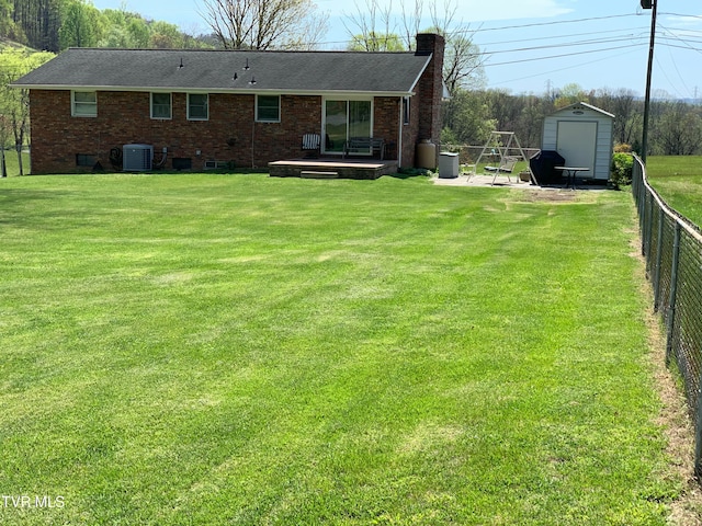 rear view of property with central AC unit, a storage unit, a patio, and a yard