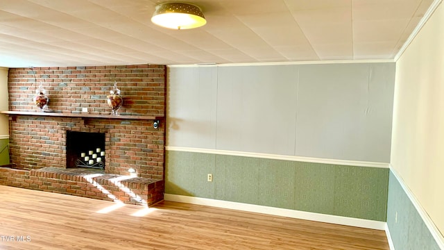 unfurnished living room featuring wood-type flooring, crown molding, and a fireplace