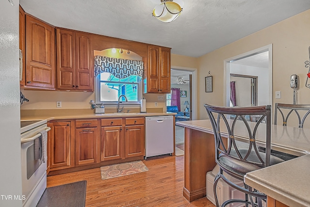 kitchen with a textured ceiling, stainless steel appliances, sink, and light wood-type flooring