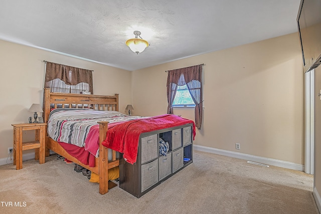 bedroom featuring a textured ceiling and light colored carpet