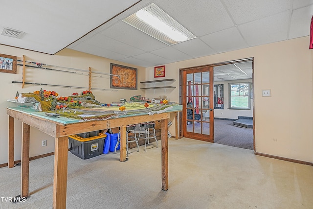 basement featuring french doors, carpet, and a drop ceiling