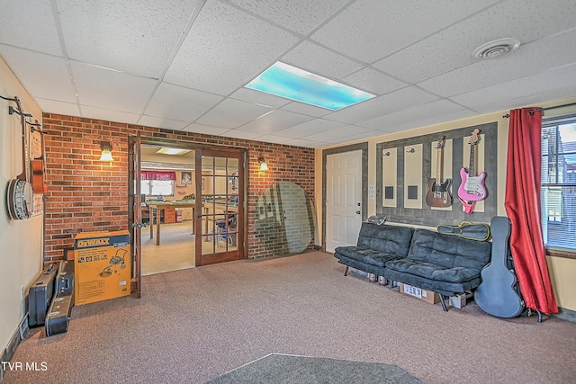 sitting room featuring a drop ceiling, carpet floors, brick wall, and french doors