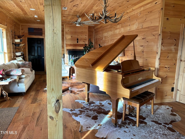 miscellaneous room featuring wood ceiling, wood-type flooring, ceiling fan with notable chandelier, and wood walls