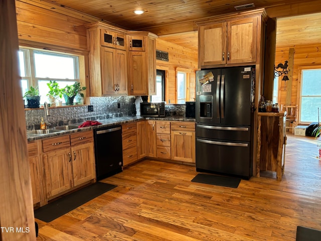 kitchen with fridge with ice dispenser, dishwasher, wooden walls, light hardwood / wood-style floors, and sink