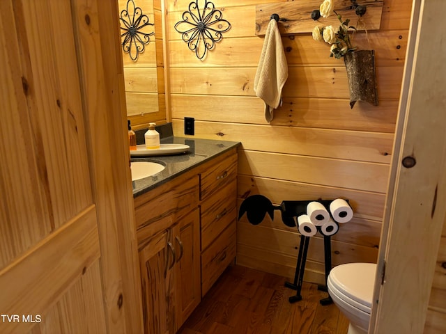 bathroom featuring vanity, hardwood / wood-style flooring, toilet, and wood walls