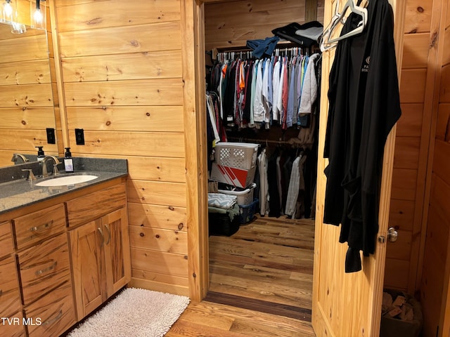 bathroom featuring vanity, wooden walls, and wood-type flooring