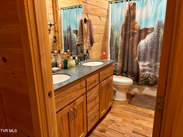 full bathroom featuring shower / tub combo, toilet, wooden walls, vanity, and hardwood / wood-style flooring