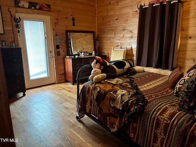 bedroom with light hardwood / wood-style flooring and wooden walls