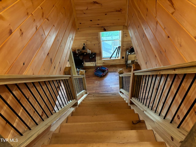 stairs with wooden walls and hardwood / wood-style flooring