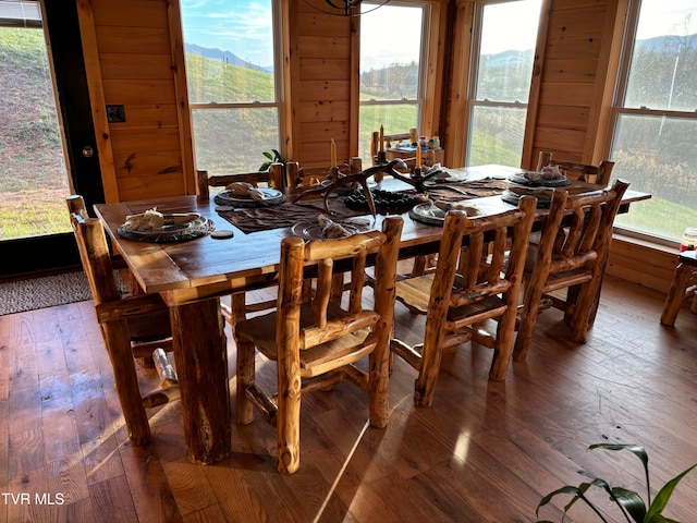 dining room featuring a mountain view, dark hardwood / wood-style floors, and wood walls