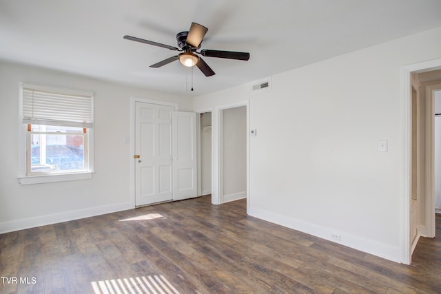 empty room with visible vents, baseboards, ceiling fan, and dark wood-style flooring