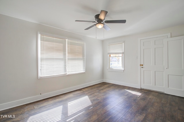 empty room featuring dark wood finished floors, baseboards, and ceiling fan