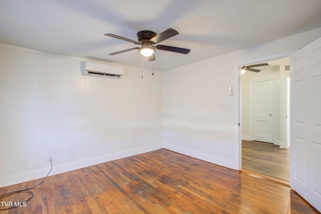 empty room with a wall unit AC, hardwood / wood-style flooring, baseboards, and ceiling fan