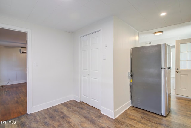 interior space featuring a wall mounted AC, freestanding refrigerator, baseboards, and wood finished floors