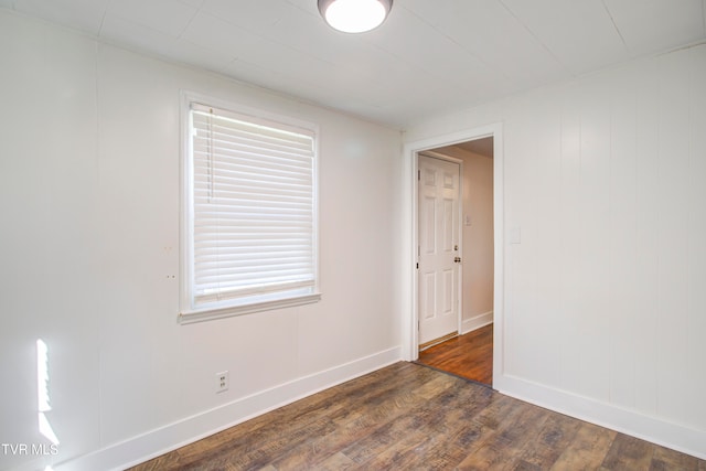 spare room featuring baseboards and dark wood finished floors